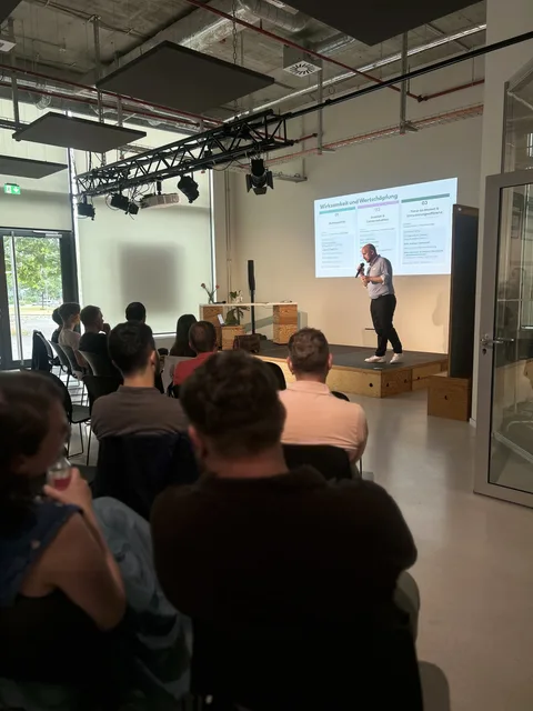 Volles Publikum beim Fachtag, auf der Bühne läuft der Vortrag